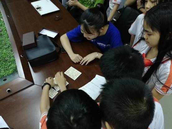 心理健康教育学生在给四年级小学生做OH牌，学生充满兴趣与好奇。.jpg